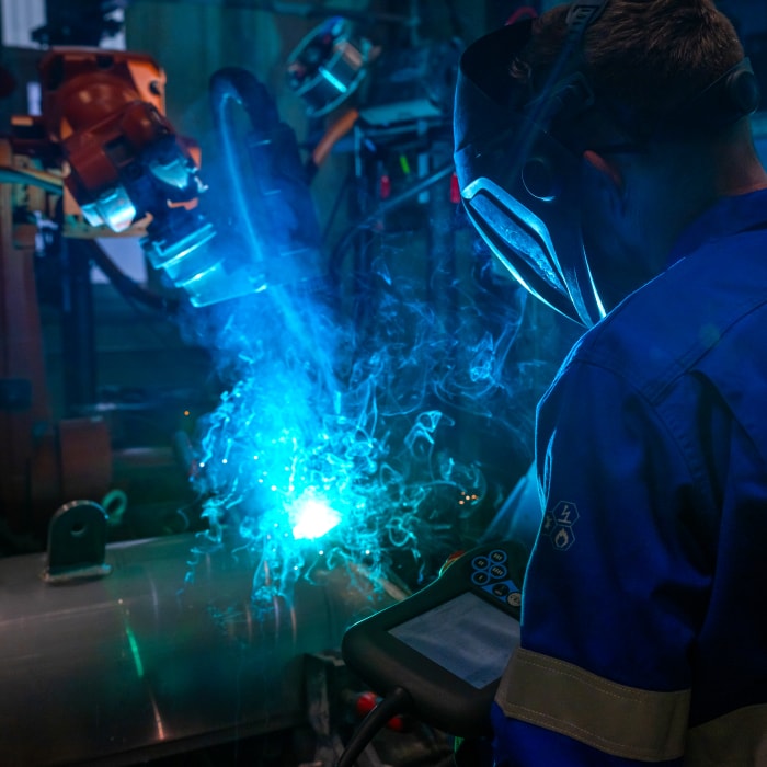 Man operating a welding robot.