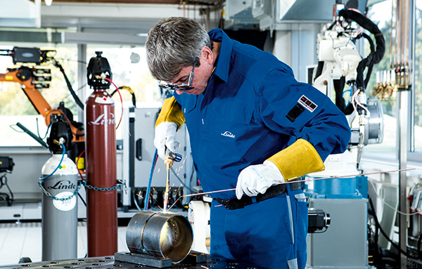 Un homme soude deux sections de tuyaux ensemble avec la technique autogène