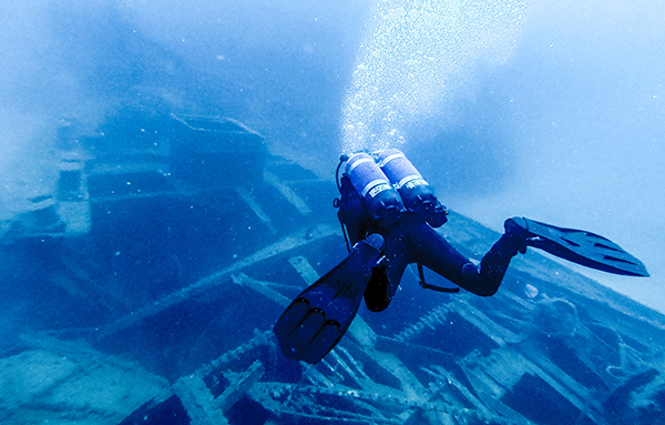 Taucher inspiziert ein Schiffswrack unter Wasser