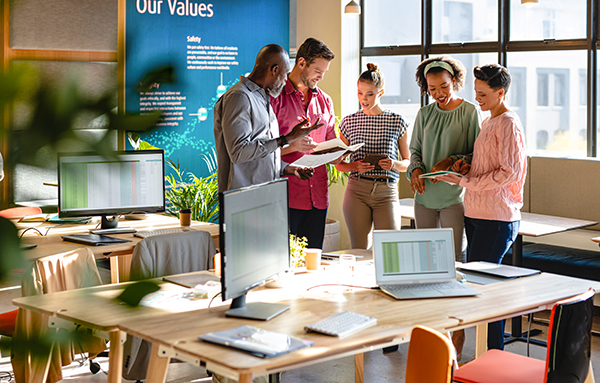 Plusieurs personnes sont debout ensemble et tiennent une réunion, symbolisant un échange informel et le travail d'équipe
