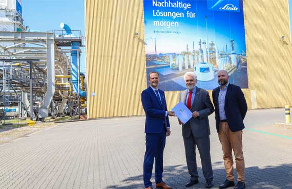 Gruppenbild mit 3 Personen vor Elektrolyseur