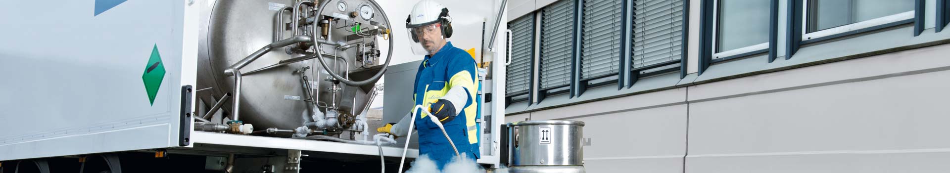 Mann in Sicherheitskleidung gießt über Lanze flüssigen Stickstoff in eine Kanne