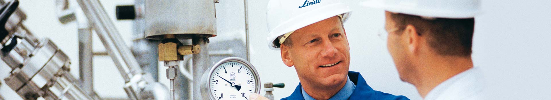 Zwei Männer mit weißem Sicherheitshelm und blauem Linde Logo unterhalten sich