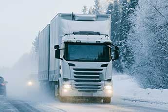LkW und Auto auf schneebedeckter Fahrbahn