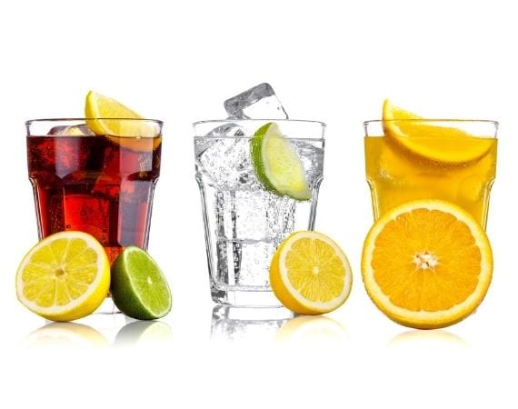 Cola, Sprudelwasser und Saft in je einem Glas dargestellt mit Orangen-, Zitronen- und Limettenscheiben dekoriert