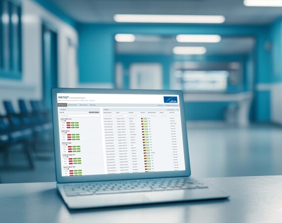 Laptop auf einem Tisch in einem modernen Klinikflur mit geöffneter Softwareoberfläche zur Anzeige von Daten und Statusübersichten.