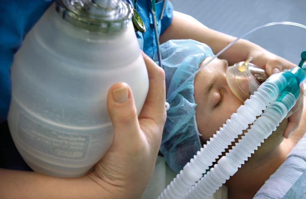 Persoon met mondkap aan beademing
